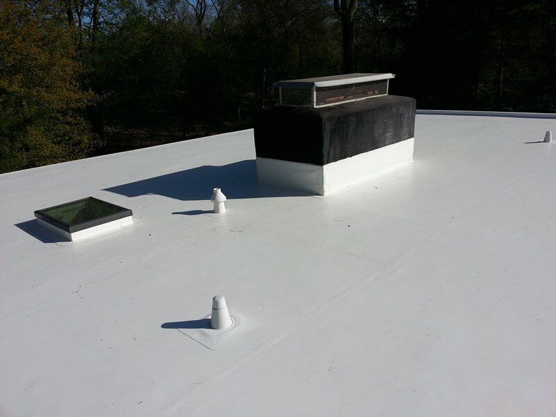 Curb-mounted skylight and a membrane-wrapped chimney flashed into a white PVC flat roof