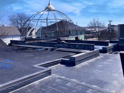 Black rubber flat roof with raised curbs and an open metal dome frame